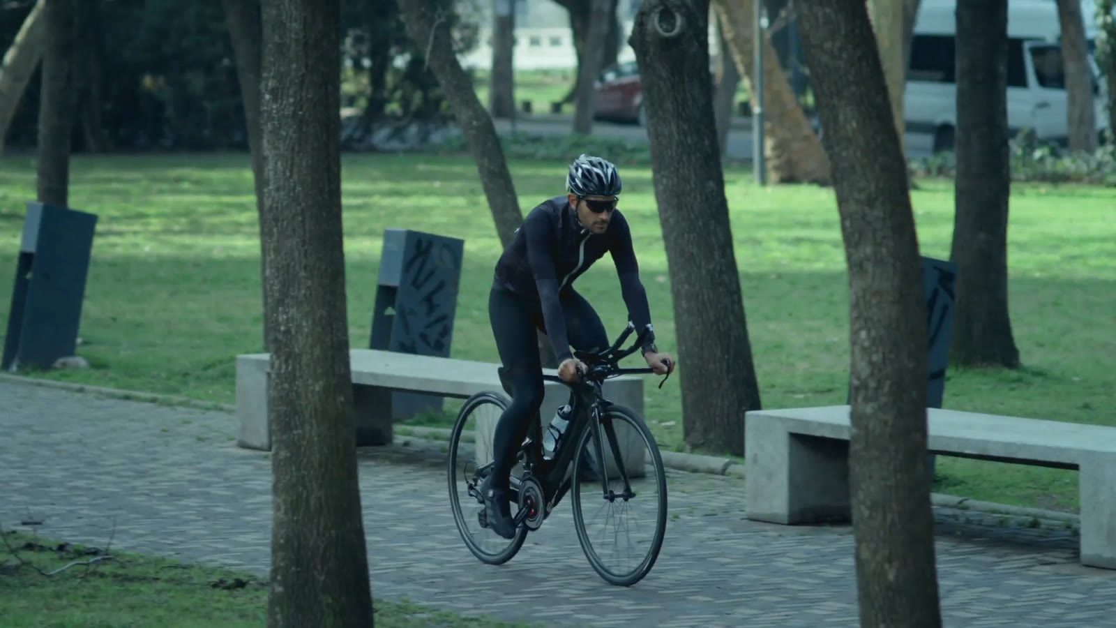 A cyclist rides through a tree-lined park