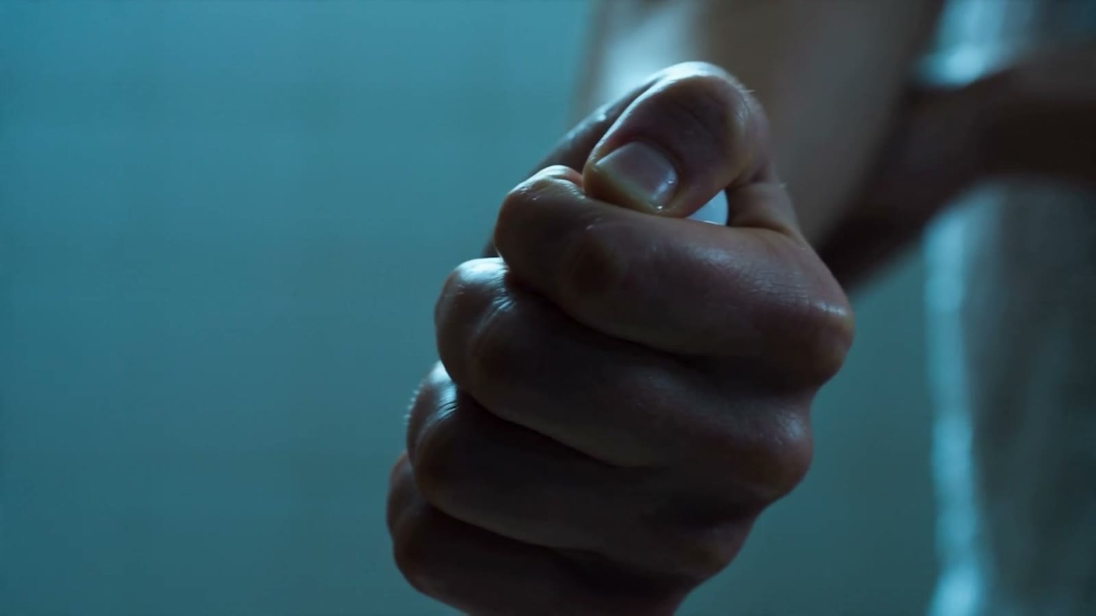 A clenched fist against a teal wall