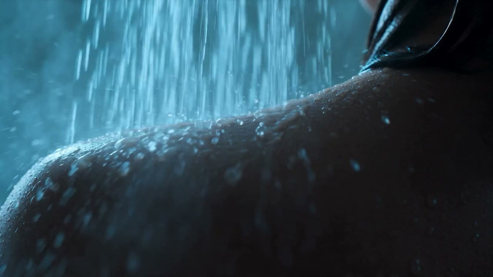Shower water shattering over a shoulder in blue backlight