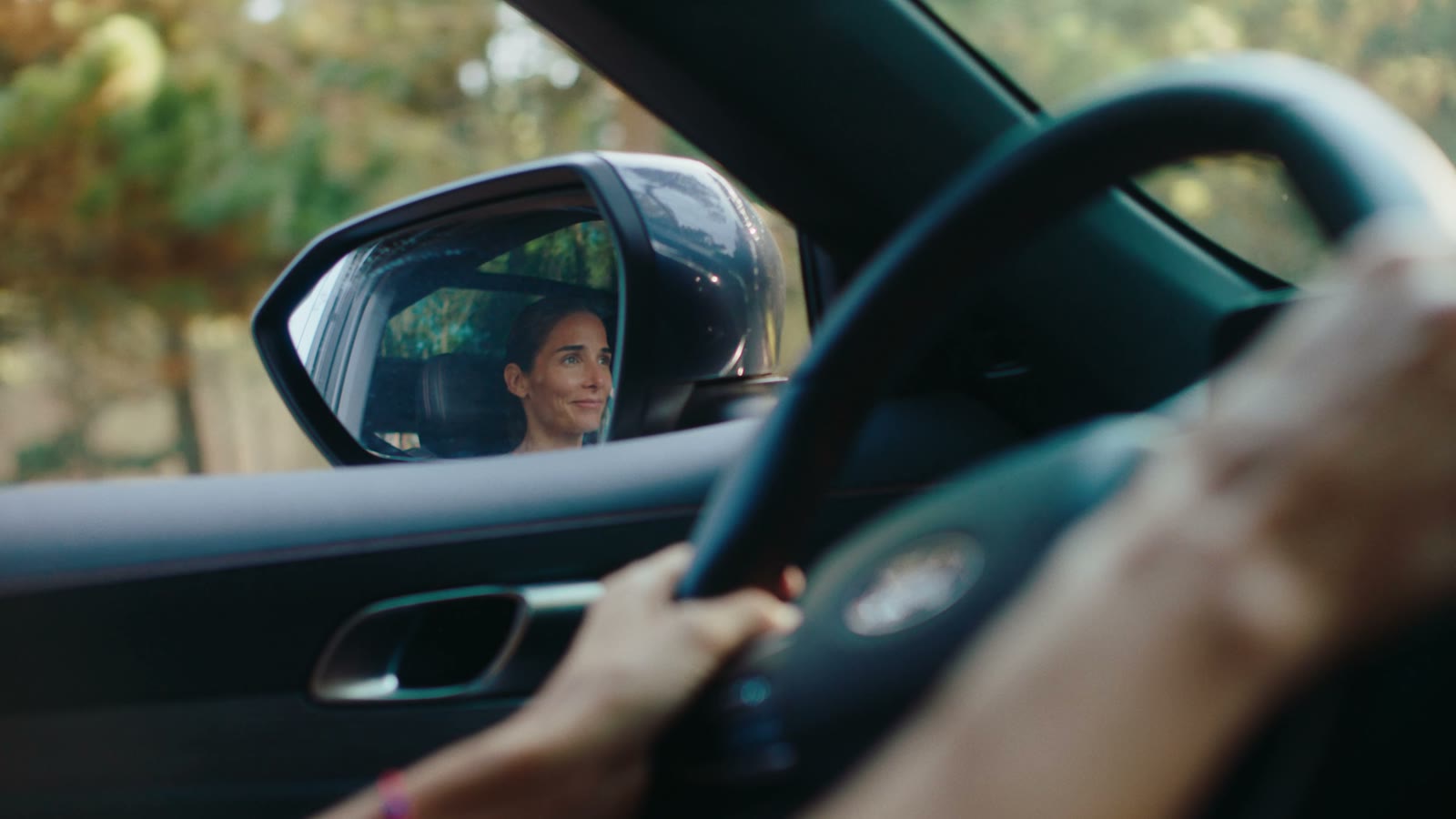 Juana Viale smiling, reflected in the car side mirror