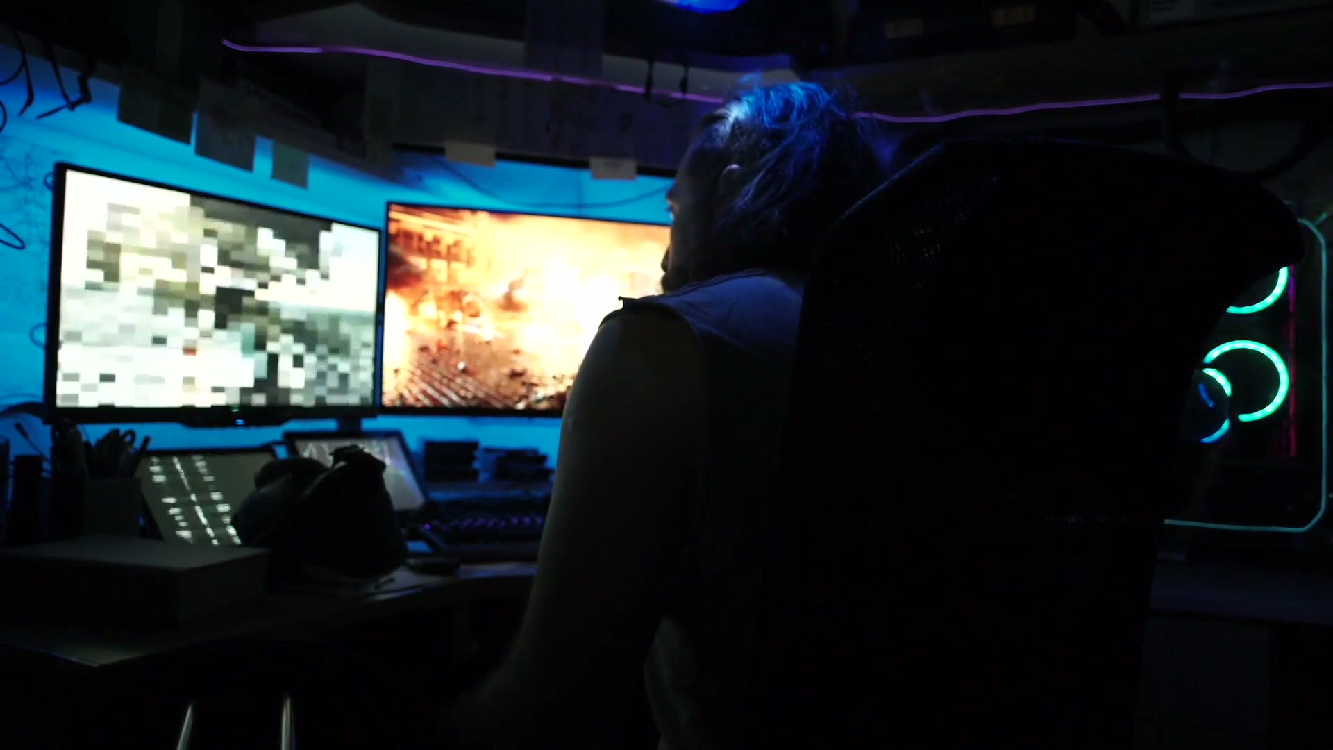 A lone silhouette wired between glowing monitors in the dark